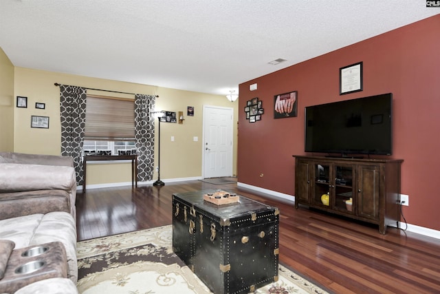 living area featuring a textured ceiling, dark wood-style flooring, visible vents, and baseboards