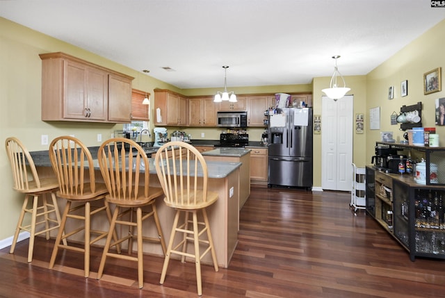 kitchen featuring dark countertops, pendant lighting, stainless steel appliances, and dark wood-style flooring