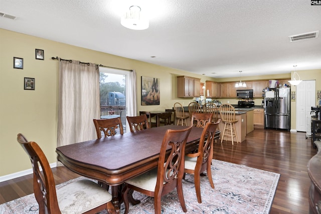 dining room featuring a textured ceiling, dark wood finished floors, visible vents, and baseboards