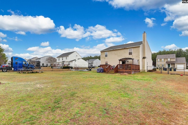 view of yard with a deck, a trampoline, fence, and a residential view