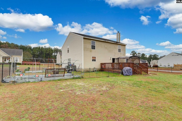 rear view of property with a vegetable garden, a chimney, a lawn, a deck, and a fenced backyard