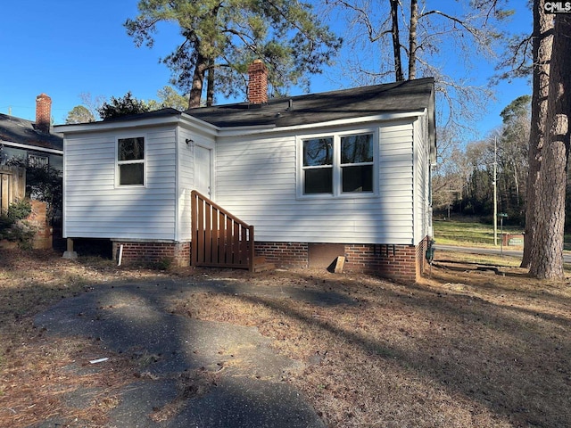 rear view of house featuring entry steps, crawl space, and a chimney