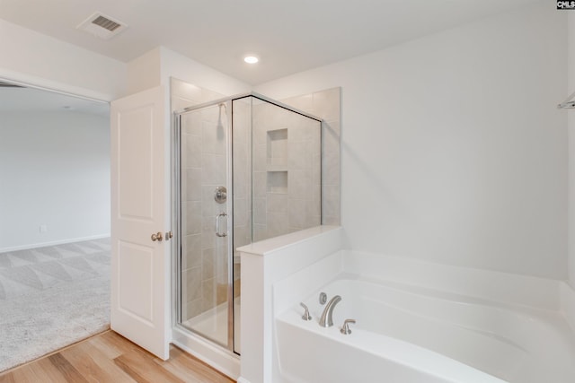 full bathroom featuring a stall shower, visible vents, a bath, and wood finished floors