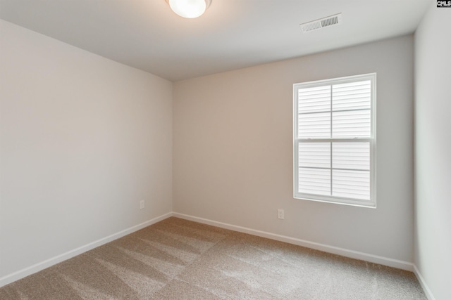 carpeted spare room featuring visible vents and baseboards