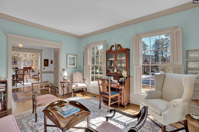 living area with ornamental molding, an inviting chandelier, and wood finished floors