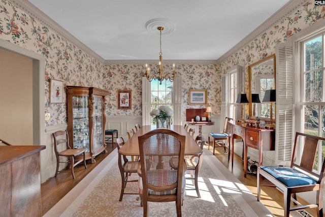 dining space featuring a chandelier, light wood-type flooring, a wainscoted wall, and wallpapered walls