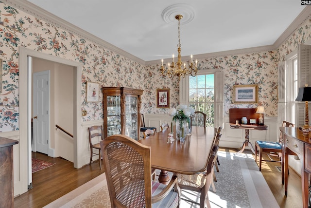 dining area featuring dark wood-style flooring, wainscoting, crown molding, and wallpapered walls