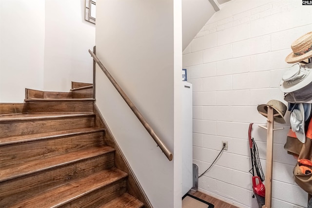 stairway with concrete block wall and wood finished floors