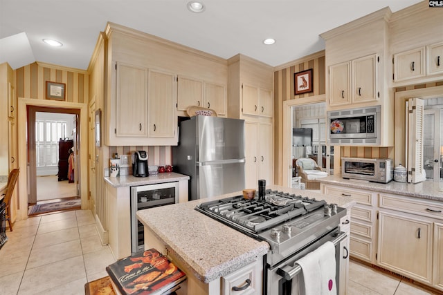 kitchen featuring light tile patterned floors, beverage cooler, stainless steel appliances, a center island, and light stone countertops