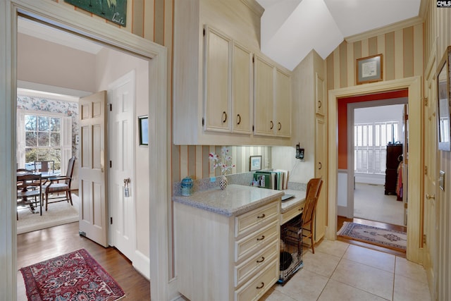 office with wallpapered walls, light tile patterned floors, vaulted ceiling, and a wealth of natural light