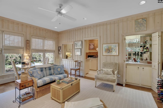 living room with light wood-type flooring, ceiling fan, and ornamental molding