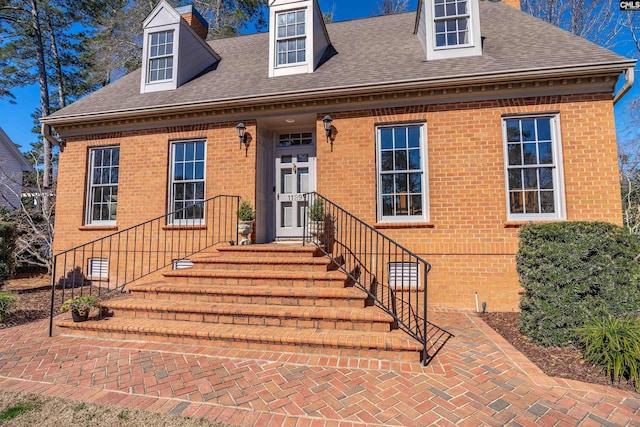 view of front facade with crawl space, brick siding, and roof with shingles