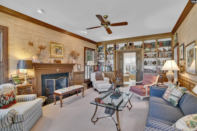 carpeted living area with ceiling fan, built in shelves, a high end fireplace, and crown molding