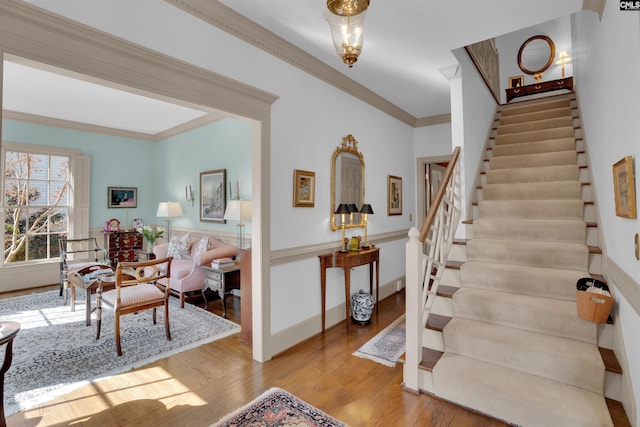 entryway with light wood finished floors, stairs, baseboards, and crown molding