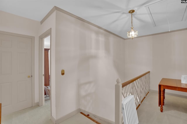 hallway featuring light colored carpet, an upstairs landing, baseboards, ornamental molding, and attic access