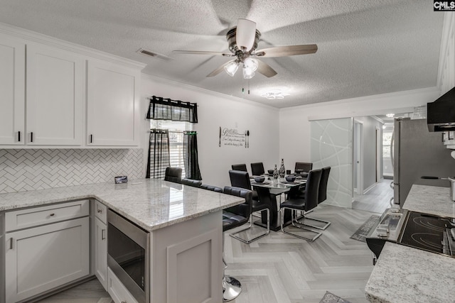 307 Wyoming Dr, Sumter, SC 29153 - kitchen with a peninsula, a healthy amount of sunlight, white cabinetry, and appliances with stainless steel finishes