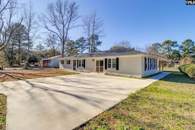 ranch-style house featuring a front yard, concrete driveway, and brick siding