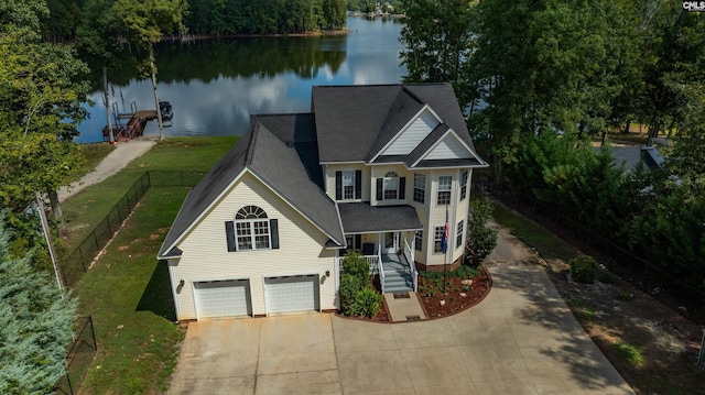 view of front of property with a water view, fence, a garage, driveway, and a front lawn