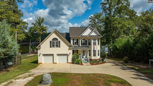 view of front of home featuring an attached garage, a water view, fence, driveway, and a front lawn