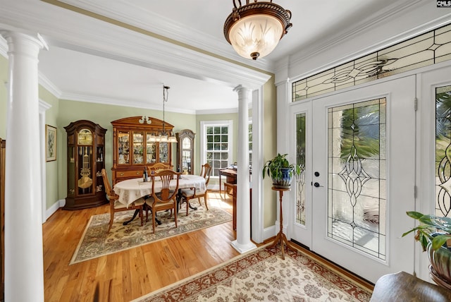 interior space featuring light wood-type flooring, ornate columns, baseboards, and ornamental molding