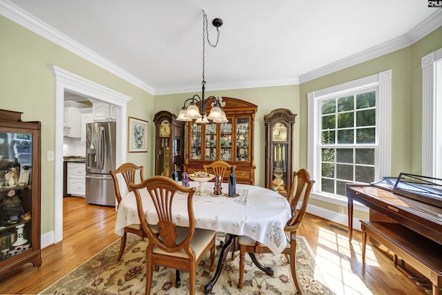 dining area featuring a chandelier, a wealth of natural light, light wood-style floors, and ornamental molding