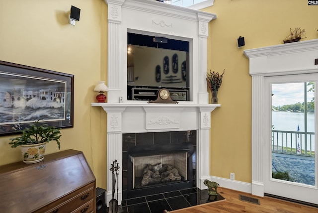 living area with baseboards, visible vents, wood finished floors, and a tile fireplace