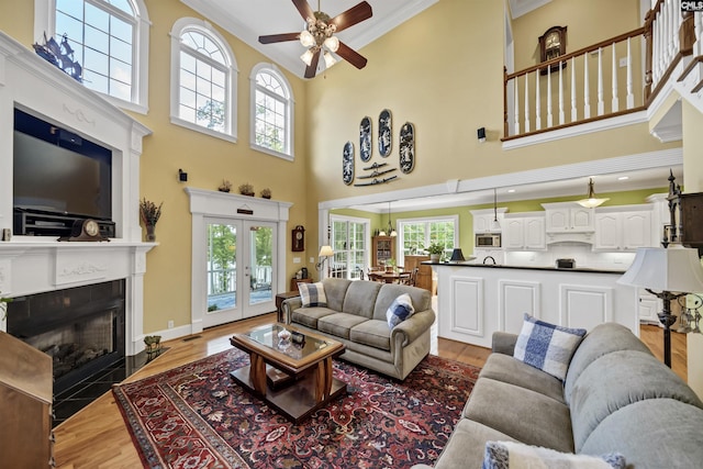 living room featuring light wood-style floors, a wealth of natural light, and crown molding