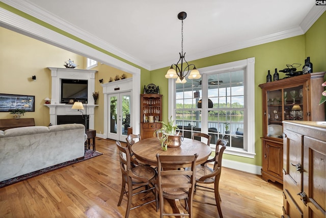 dining area featuring ornamental molding, light wood finished floors, a fireplace, and a chandelier