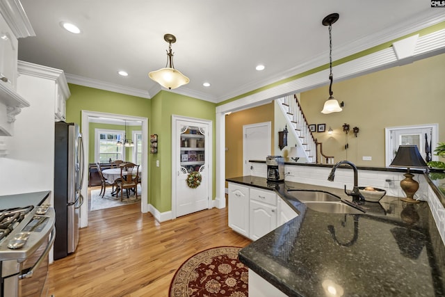 kitchen featuring appliances with stainless steel finishes, white cabinetry, dark stone counters, and decorative light fixtures