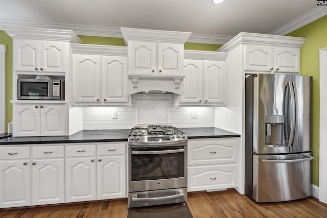 kitchen featuring stainless steel appliances, dark countertops, white cabinetry, and custom range hood