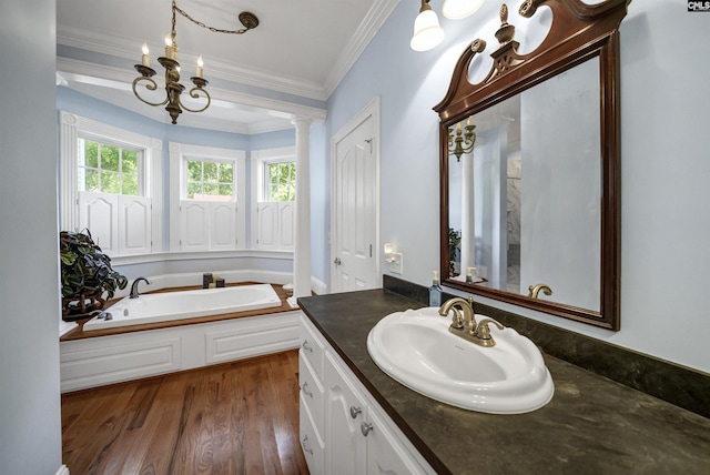 bathroom featuring decorative columns, wood finished floors, crown molding, vanity, and a bath