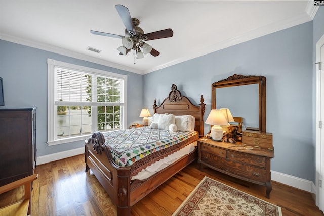 bedroom featuring visible vents, crown molding, baseboards, and wood finished floors