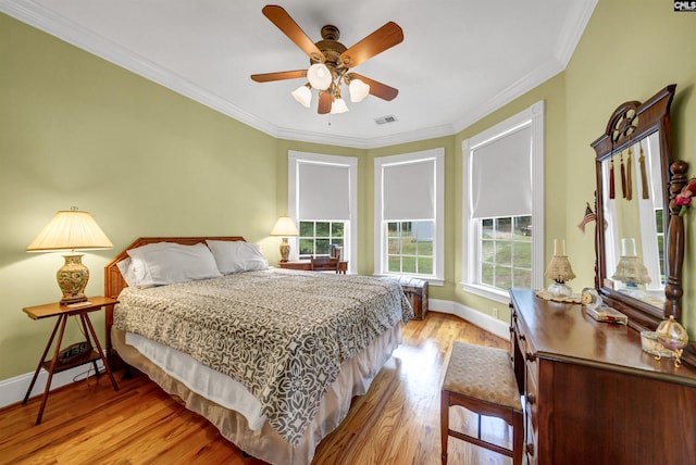 bedroom featuring crown molding, visible vents, light wood-style floors, ceiling fan, and baseboards