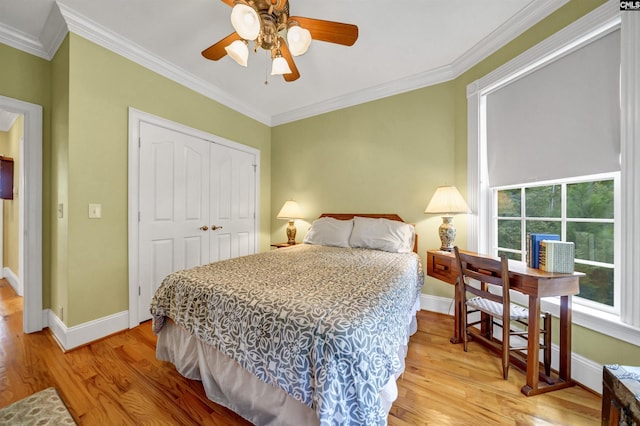 bedroom featuring baseboards, light wood finished floors, a closet, and crown molding