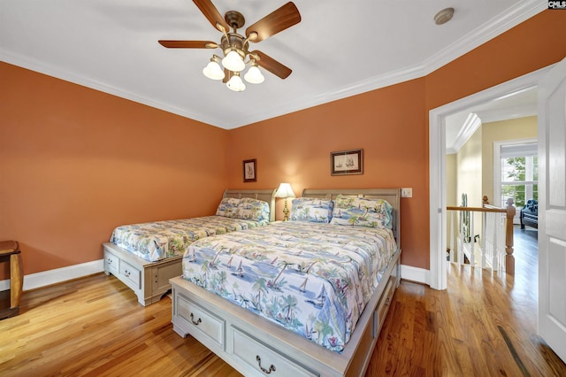 bedroom with ceiling fan, ornamental molding, light wood-type flooring, and baseboards