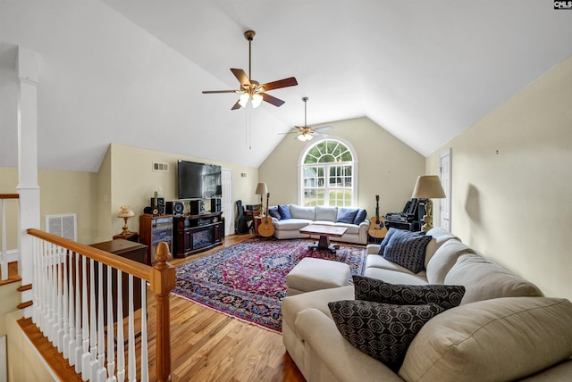 living area featuring lofted ceiling, wood finished floors, visible vents, and ornate columns