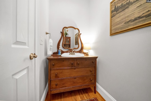 bathroom with wood finished floors, vanity, and baseboards