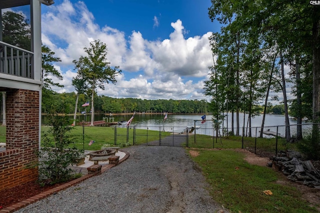 view of yard with a water view, a gate, a fire pit, and fence