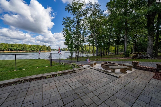 view of patio with an outdoor fire pit, a water view, and fence