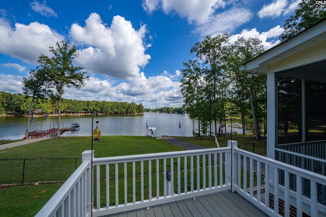 deck featuring a water view, fence, a boat dock, and a yard