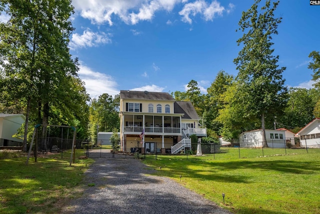 view of front of house featuring a front yard, a sunroom, fence, and stairs