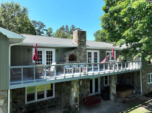 rear view of house featuring french doors, a chimney, board and batten siding, a patio area, and stone siding