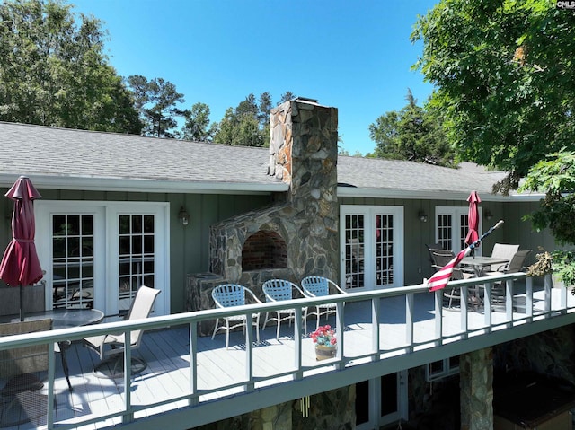 back of property featuring a deck, french doors, roof with shingles, and a chimney