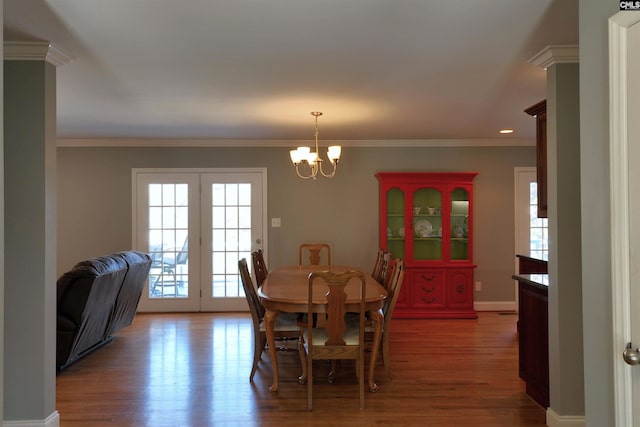 dining space with baseboards, ornamental molding, wood finished floors, and a notable chandelier