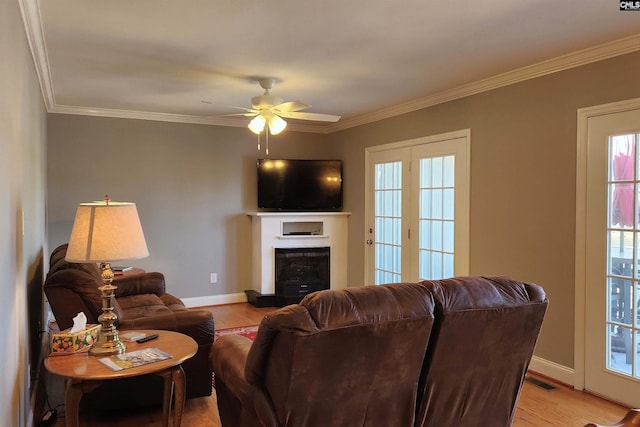 living area featuring a fireplace with raised hearth, light wood-type flooring, and crown molding