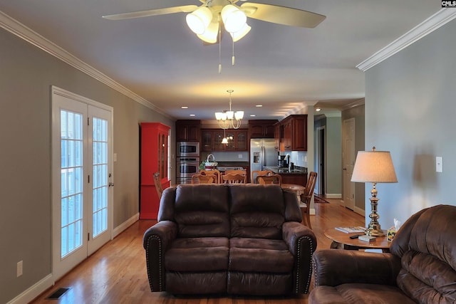 living room with light wood-type flooring, baseboards, visible vents, and crown molding