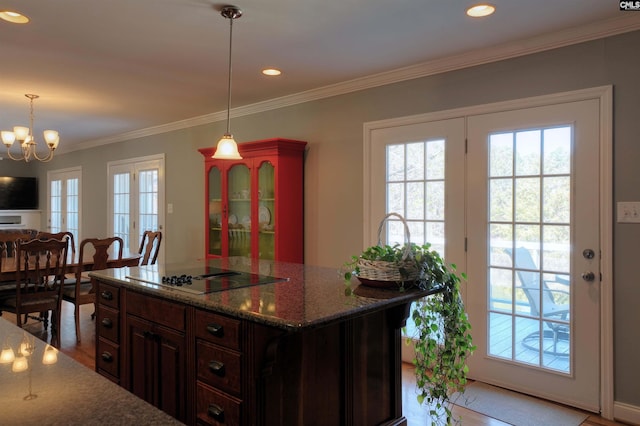 kitchen featuring dark brown cabinetry, plenty of natural light, dark stone counters, a center island, and black electric cooktop