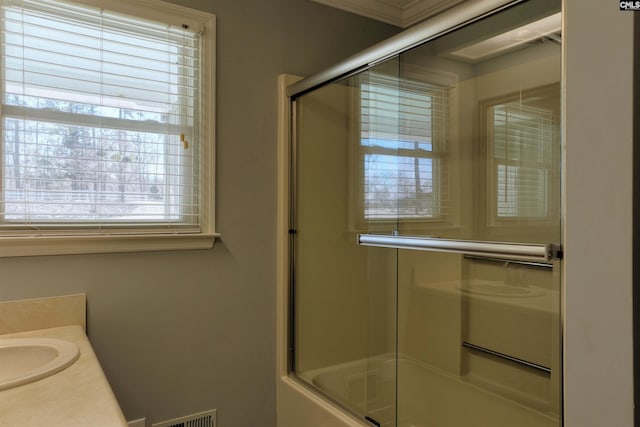 bathroom with enclosed tub / shower combo, visible vents, and vanity