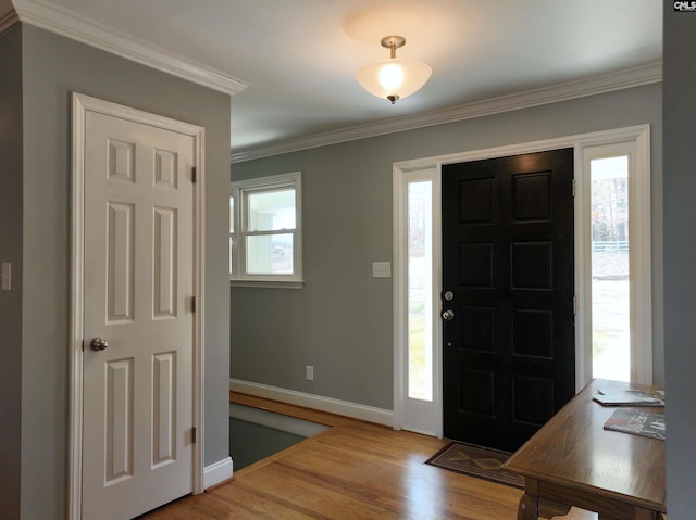 entryway with ornamental molding, light wood-style flooring, and baseboards