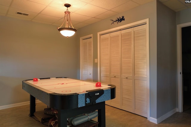 game room with a drop ceiling, visible vents, and baseboards